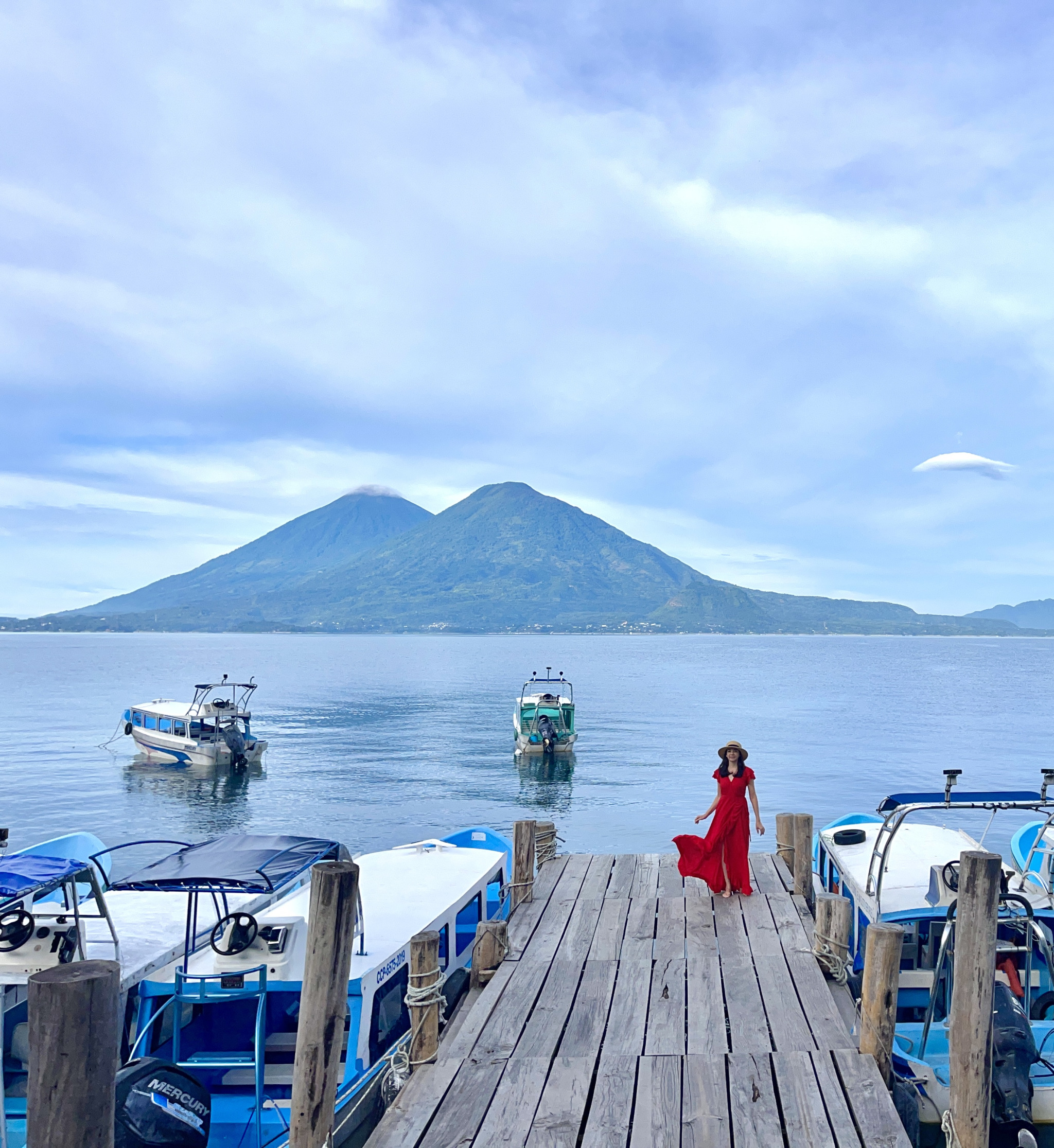 Traveler standing on a dock overlooking Lake Atitlán and volcanoes